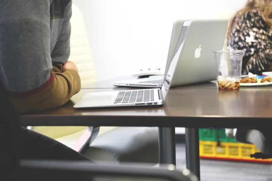 A laptop open on a desk mid-job, with someone working beside it
